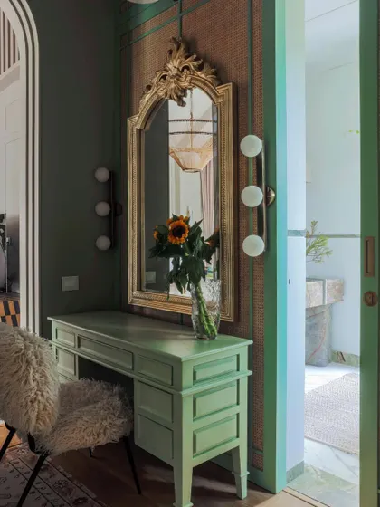 The master suite in Summer Haus includes this elegant vanity area. The design combines a vintage-inspired mirror with modern lighting and a custom desk, leading into a spacious walk-in closet.