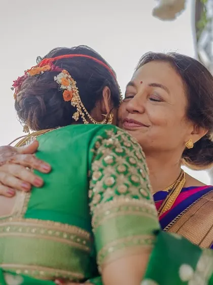 A heartfelt hug between the bride and her mother. This angle showcases the beautiful floral arrangement on her traditional bridal bun.