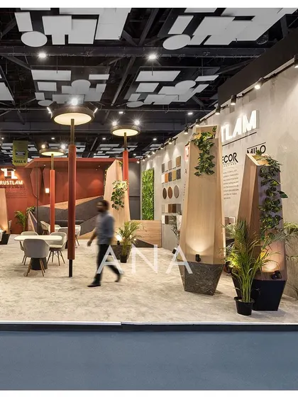 A visitor walks through the Trustlam '23 space, demonstrating the open and interactive nature of the design. The lamp-post sculptures are integrated with planters, adding a natural element to the abstract design.