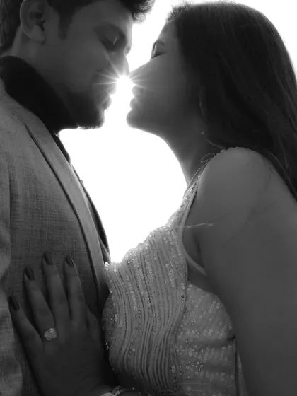 A dramatic black and white silhouette of a couple about to kiss, with the sun creating a starburst effect between them.