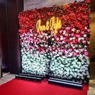 A stunning photo wall made of red, pink, and white roses. The "Love & Light" neon sign adds a modern and romantic touch, making it a very popular spot for selfies.