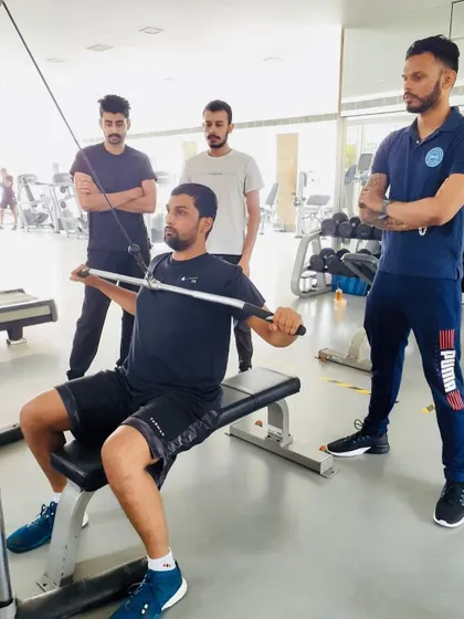 Supervising a coach performing a lat pulldown, ensuring they maintain proper form throughout the movement.