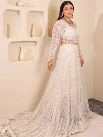 For the modern bride who dreams in white. This elegant pearl and sequin lehenga with a dramatic trail is perfect for a reception or engagement, proving that bridal glam comes in every color.