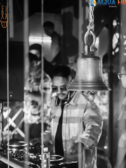 An artistic black and white shot of me behind the decks at The Fixx, seen through a reflection with the club's signature bell.