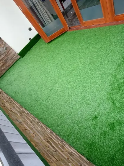 A different perspective of the same enclosed balcony, showing the texture and consistent color of the high-quality synthetic grass I use.