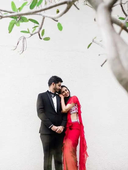 A tender moment between the couple, framed by a tree, during their outdoor reception.