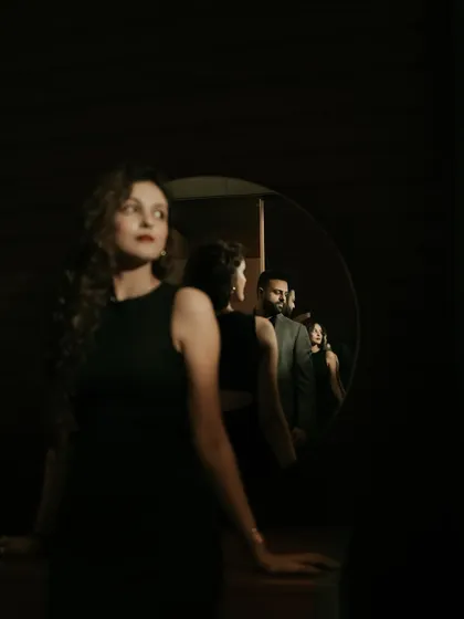 An artistic and conceptual portrait using a mirror to create layers of reflection. This dramatic, low-light shot plays with focus and perspective to tell a complex visual story.