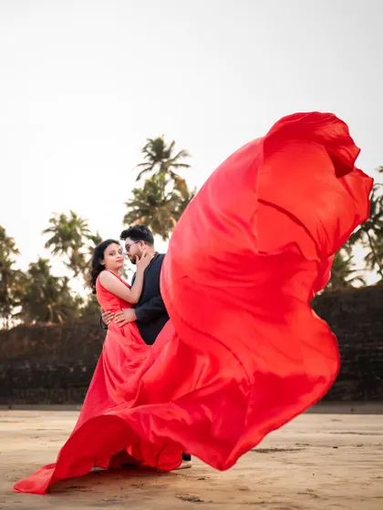 A whirlwind of romance. The billowing red trail of her gown creates a spectacular, dramatic effect for this beach pre-wedding shoot.