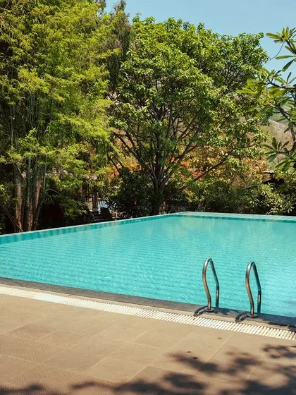 The crystal-clear water of our pool invites you for a swim. Framed by trees, it's a serene spot to relax and escape the heat.