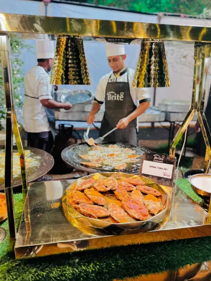A live tawa station where a chef is frying Surmai fish for guests.