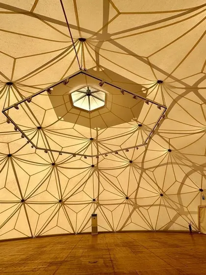 The interior of the Buckminster Fuller dome. The intricate pattern of the structure creates a beautiful play of shadow and light, transforming the ceiling into a work of art itself.