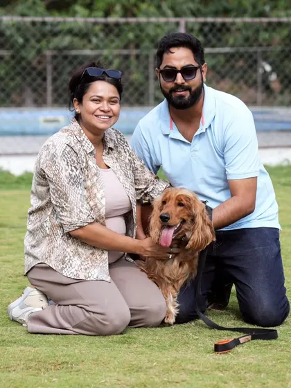 A happy couple posing with their adorable Cocker Spaniel. It's a perfect day out for the whole family.