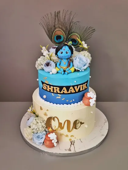 Little Kittu! A beautiful two-tier cake for Shraavik's first birthday, with a Little Krishna theme. This vanilla and chocolate truffle cake features a hand-sculpted Krishna, peacock feathers, and floral details.