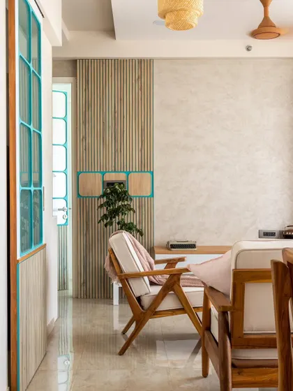The subtle play of light and color is key. The teal-framed doors with chequered patterns and wooden louvers bring a unique personality to this Japandi-inspired living space.