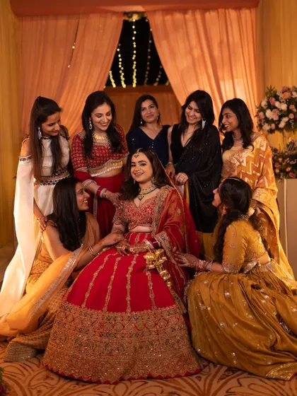 Surrounded by her bridesmaids, our bride Shivali shines in a traditional red lehenga. We styled her dupatta as a veil to keep her hands free, ensuring she could enjoy her evening with comfort and ease.
