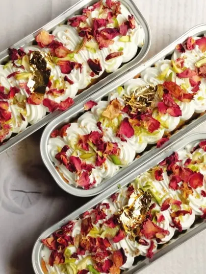 An overhead view of the Rose & Pistachio Tres Leches Boats for Eid, showing the beautiful pattern of rose petals, pistachios, and gold leaf on top of the cream.