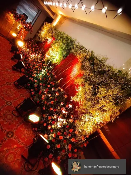 For a touch of luxury, nothing beats a dense wall of fresh flowers. This pathway is lined with thousands of red roses and baby's breath, lit by spotlights to create a rich, romantic atmosphere for a wedding or an elegant party.