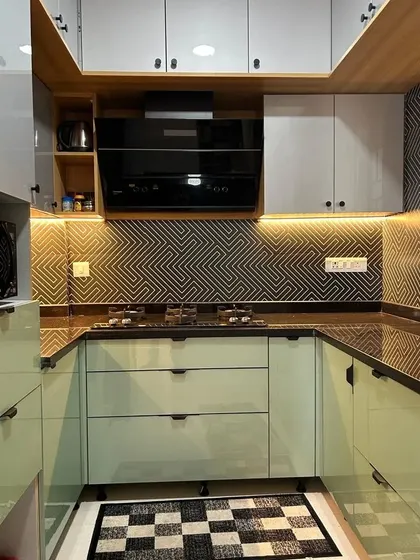 A close-up of the cooking area, featuring a sleek black chimney and hob. The under-cabinet lighting not only illuminates the workspace but also highlights the beautiful texture of the backsplash tiles.