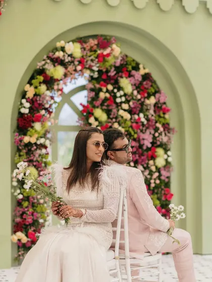 The happy couple poses for a photo in front of a floral arch.