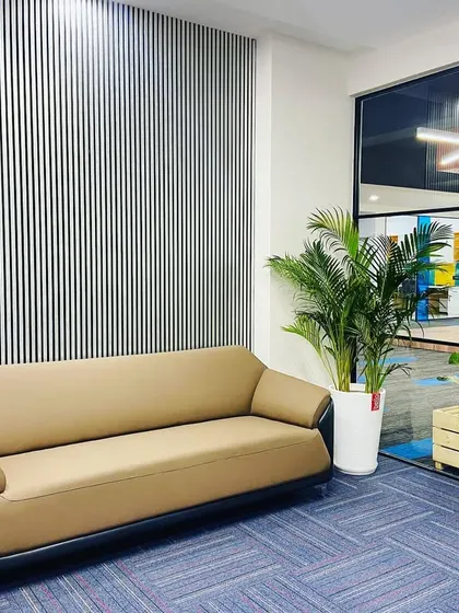 This lounge area is positioned with a clear view into the main workspace, framed by indoor plants. This creates a pleasant transition zone that feels connected to the rest of the office.