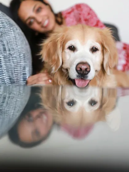 A creative reflection shot of Abby the golden retriever with her human, Anjana, creating a unique and artistic family portrait.