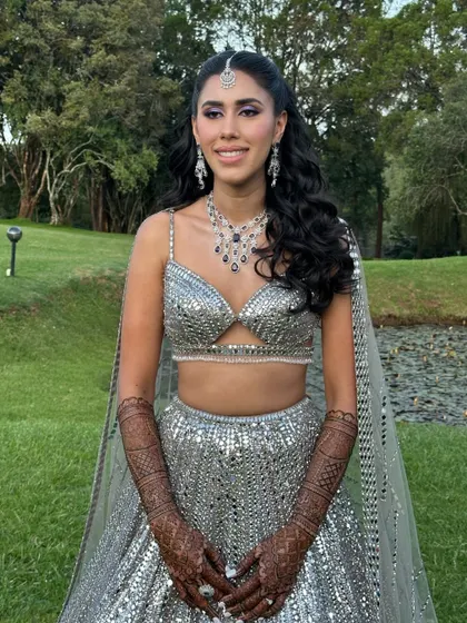 The full sangeet look in an outdoor setting. The makeup is fresh and vibrant, matching the energy of the event.