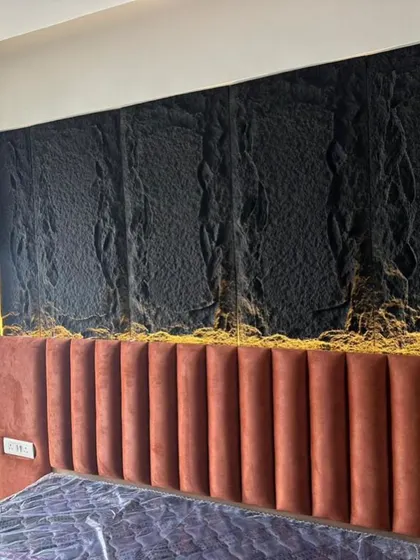 A close-up of the custom headboard and wall treatment from a recent project. This shot details the texture of the black wall panel and the vertical tufting of the rust-colored velvet headboard.