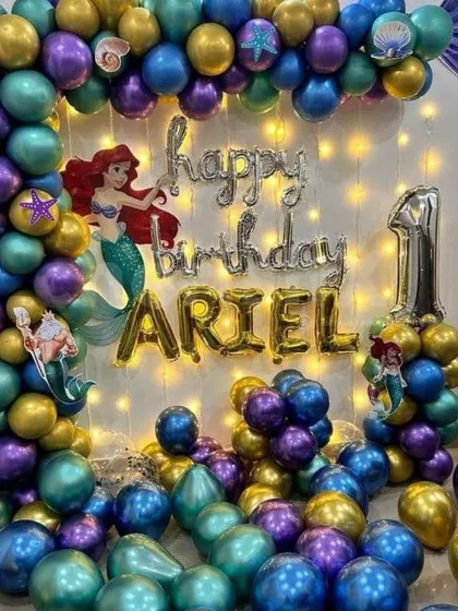 For a little girl's first birthday, I did this magical Little Mermaid theme. The balloon garland uses purple, teal, and gold balloons with seashell details. I also added Ariel character cutouts and fairy lights behind the 'Happy Birthday' foil balloons to make it sparkle.