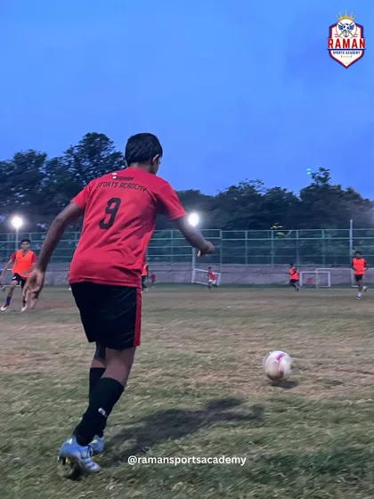 A young player in our iconic red jersey prepares to strike the ball during an evening training session.