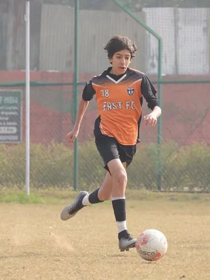 A young player driving forward with the ball at his feet during the Gurgaon Winter Cup.