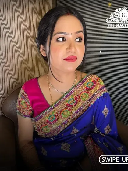 A side profile of this elegant saree look. The makeup is soft and radiant, with a focus on glowing skin and a classic red lip.