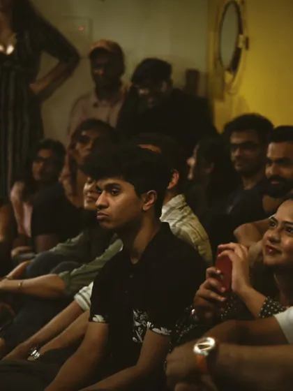 An audience completely captivated by the performance. The warm, dim lighting and cozy seating create the perfect environment for an intimate gig.