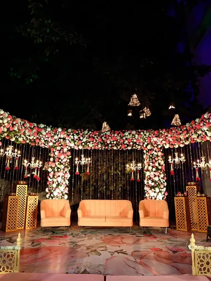 A stunning floral stage for a wedding reception at The Park Hotel lawns. The entire backdrop is a dense wall of pink and white flowers, with elegant peach-colored seating for the couple.