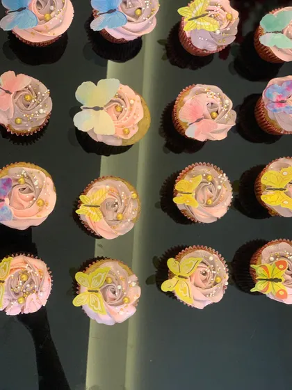 These butterfly cupcakes are perfect for an elegant celebration. Each cupcake has a soft buttercream rose base, adorned with delicate, edible wafer butterflies in various colors, creating a beautiful and whimsical dessert display.