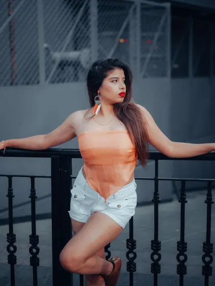 A portrait of a model leaning against a railing. The cool color tones and her confident pose create a chic and modern urban fashion shot.