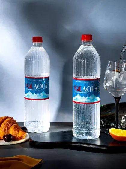 A sophisticated shot of Volaqua mineral water being poured into a wine glass. Paired with a croissant, this image elevates the simple act of drinking water into a more refined experience.