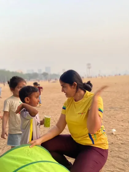 It's not just about the activities, it's about the connection. A coach takes a moment to chat with a young guest at a beach birthday party, making sure everyone feels included and happy.