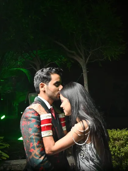 A tender moment captured at night, where the groom kisses his bride's forehead, symbolizing care and affection.