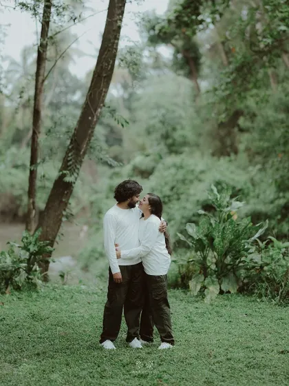 The couple embracing in a lush green forest, a moment of quiet intimacy in nature.