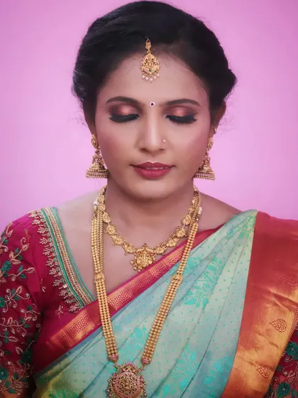 Sapna ready for her brother's wedding. Her makeup features a warm, shimmery eyeshadow and a soft red lip, which beautifully complements her light blue silk saree and traditional gold jewelry.