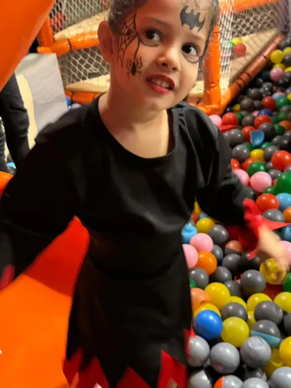 A little bat with spooky face paint ready to enjoy the ball pit. Even in costume, the kids can't resist the fun of the play zone.