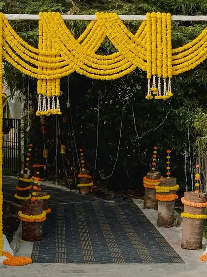 A vibrant entrance arch for a Haldi or Mehendi ceremony, constructed entirely from bright yellow marigold garlands. This cheerful and traditional design instantly sets a festive and joyful mood.