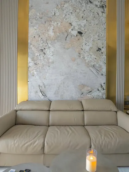 The den bedroom in the 'Urban Oasis' project, designed as a multi-functional space. A comfortable leather sofa is set against a wall with abstract art and metallic gold accents.