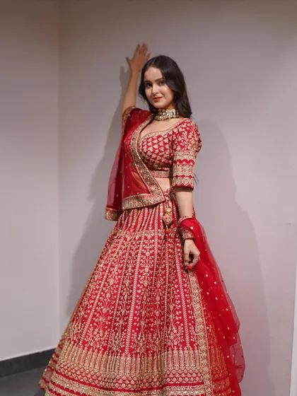 For the bride who loves classic elegance. This red lehenga is covered in detailed gold threadwork, creating a rich and luxurious texture that is perfect for your big day.
