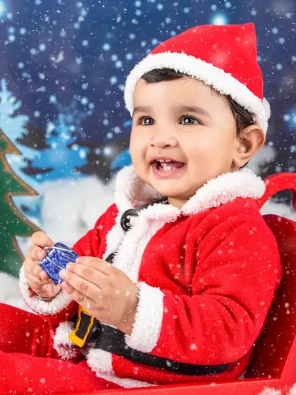 A happy little Santa playing with a toy in his sleigh. The falling snow effect adds a touch of magic.
