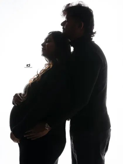 A quiet and tender silhouette. The focus is entirely on the couple's embrace and the life they are waiting for, creating a timeless and artistic maternity photo.