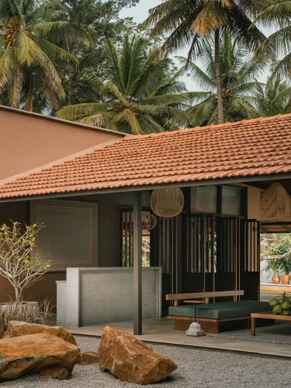 The outdoor reception area is nestled among natural boulders, with a backdrop of tropical palm trees. This space serves as a welcoming entry point, immediately establishing the home's connection to its site.