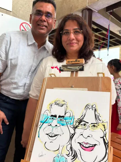 A proud artist moment, posing with a happy couple and their finished caricature at the alumni event.