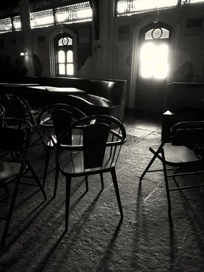 The silhouette of a chair against the light from a distant doorway, capturing the moody and atmospheric quality of the interior.