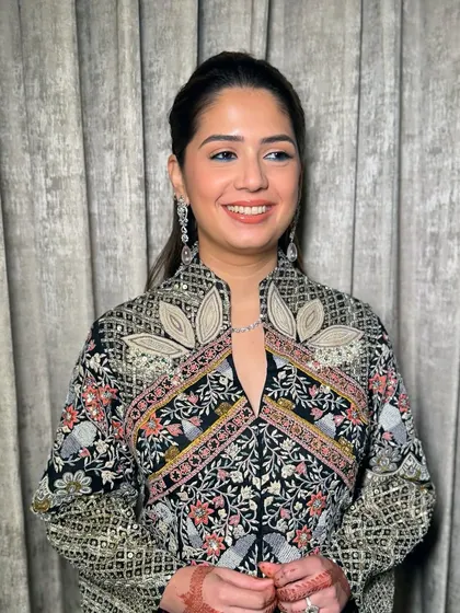 A smiling shot of this chic evening look. The makeup is clean and defined, letting her natural beauty and the statement outfit shine.